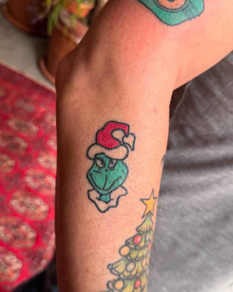 Hand poked style Grinch portrait tattoo located on the forearm (healed).