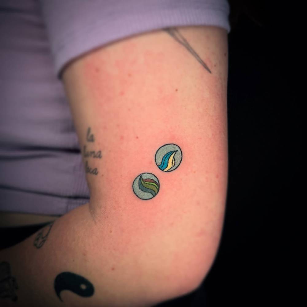 Hand poked marbles tattoo in illustrative style done on the tricep.