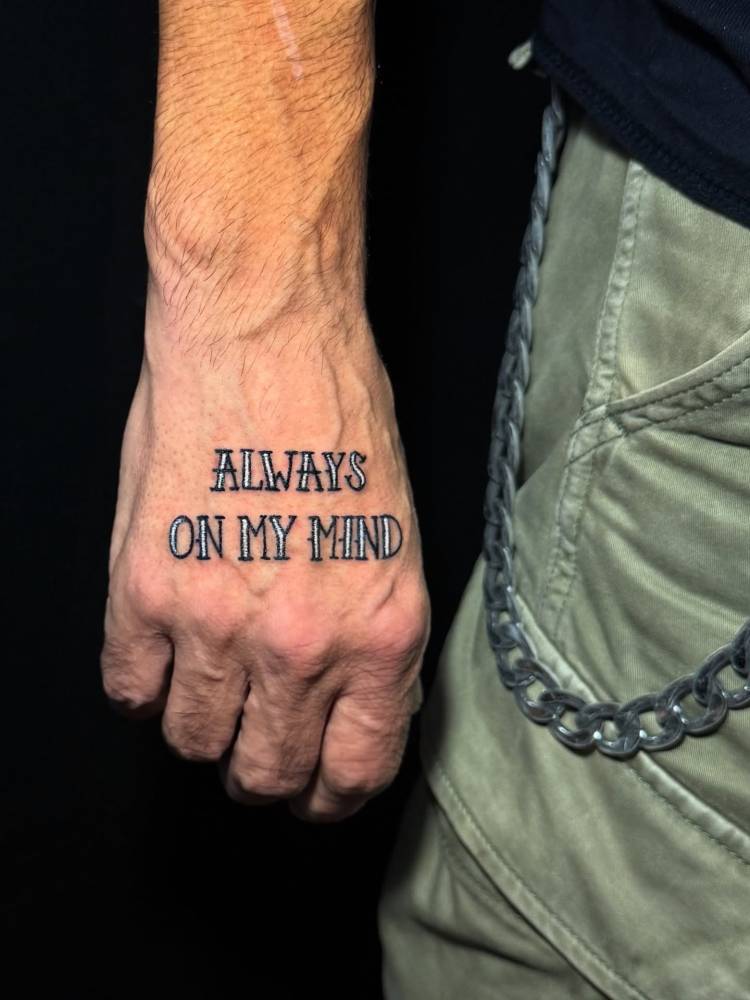 "Always on my mind" lettering tattoo placed on the hand.