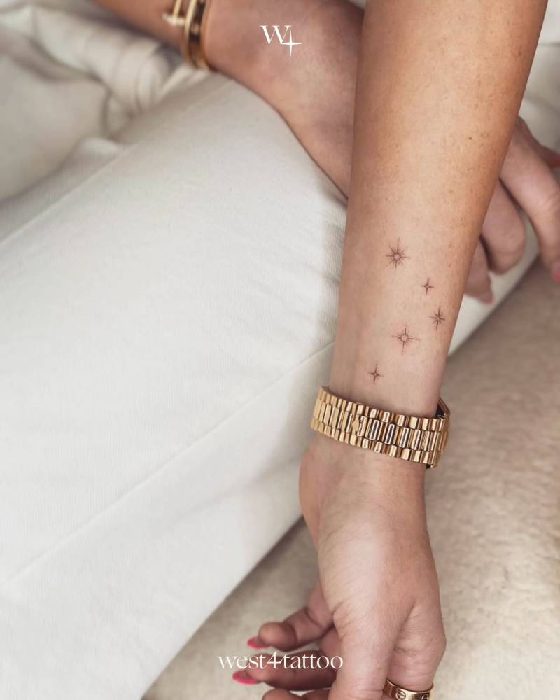 Sparkling stars tattoo located on the wrist, minimalistic style.