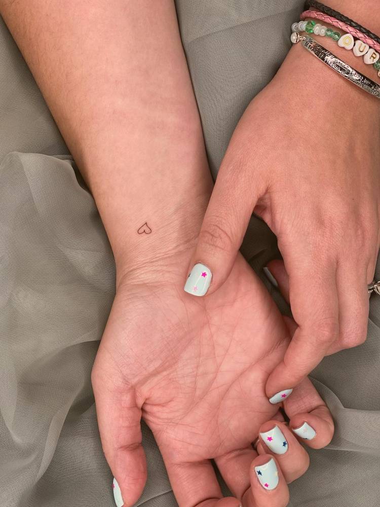 Tiny minimalistic heart tattooed on the wrist.