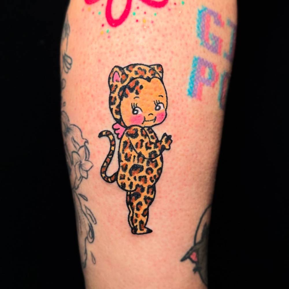 Leopard kewpie tattoo located on the calf, cartoon style.