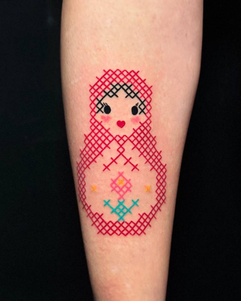 Matryoshka doll tattoo in cross stitch style placed on the shin.