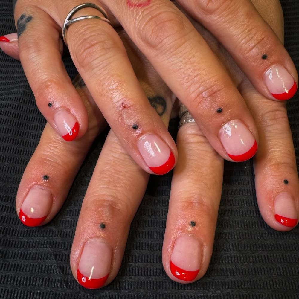 Hand poked dots tattoo located on the finger, minimalistic style.