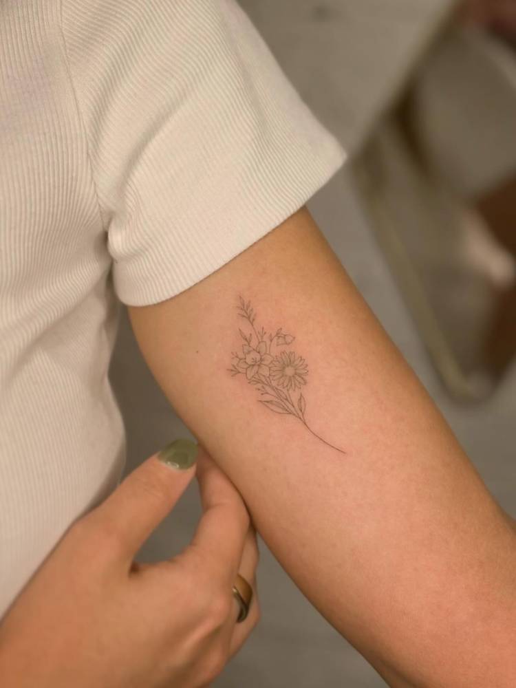 Flower bouquet in fine line style tattooed on the inner arm.