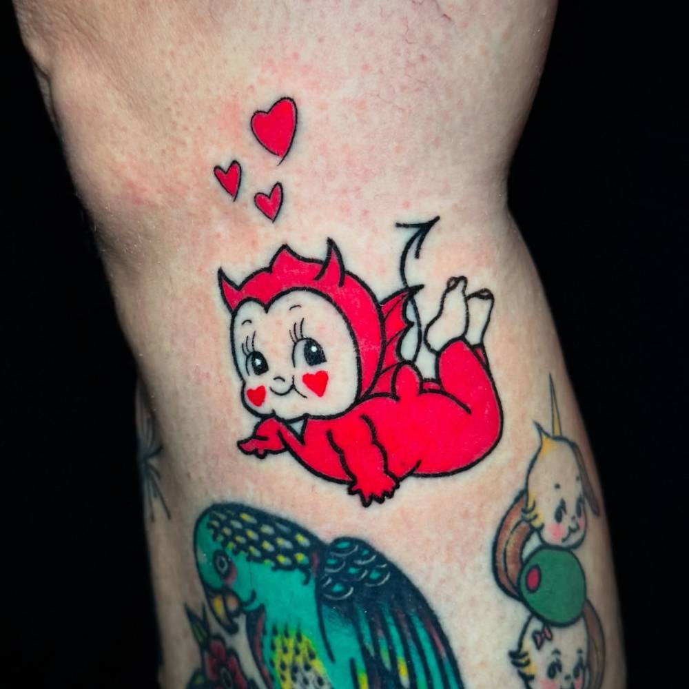 Devil kewpie tattoo in cartoon style located on the calf.