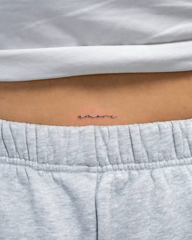 Handwritten font word "amore" tattooed on the lower back.