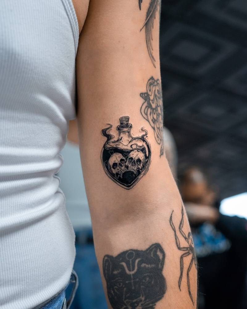 Illustrative style poison bottle tattoo located on the bicep.