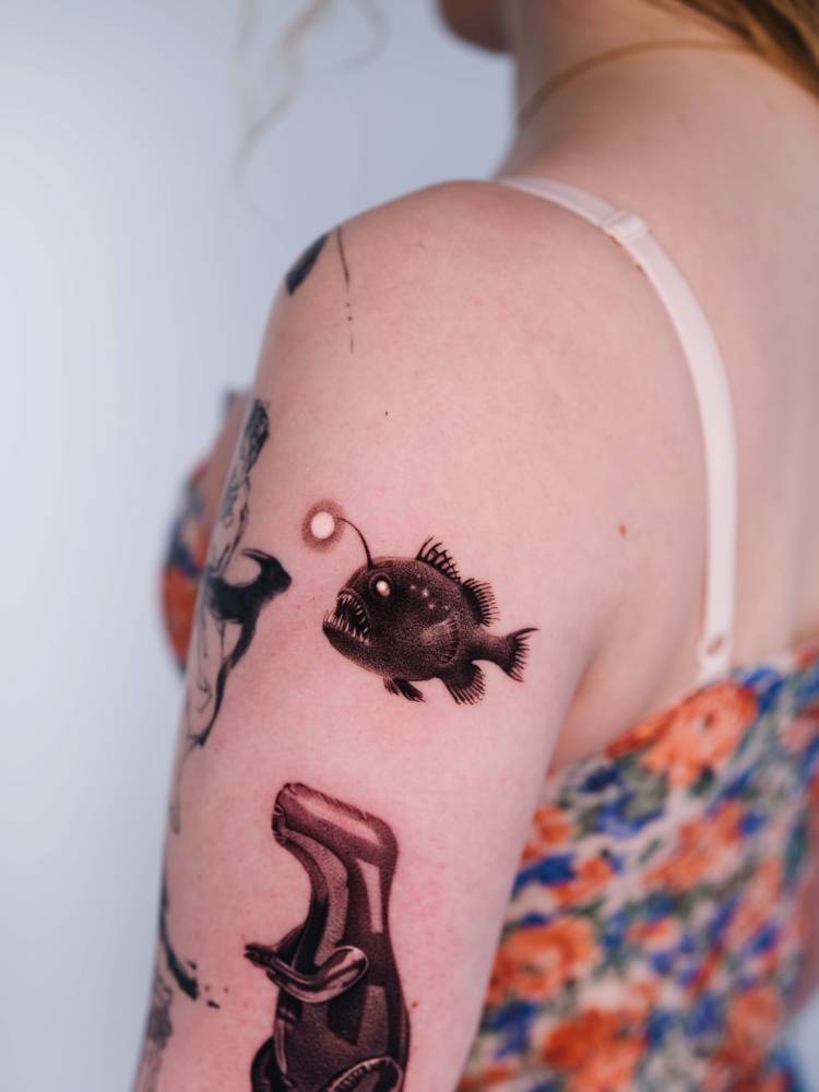 Anglerfish tattoo located on the upper arm, micro-realistic style.