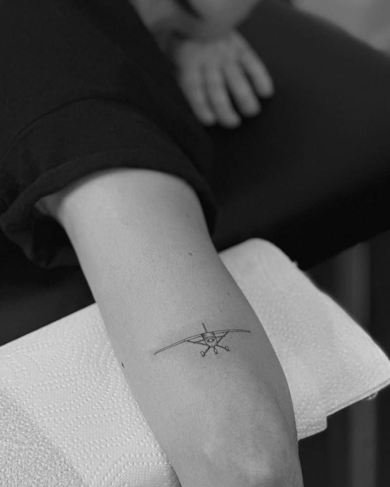 Fine line plane tattoo located on the tricep.