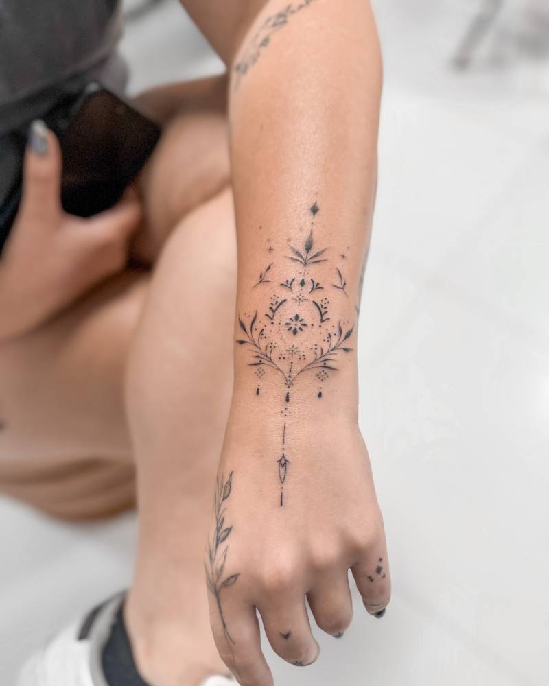 Ornamental bracelet tattoo located on the wrist.