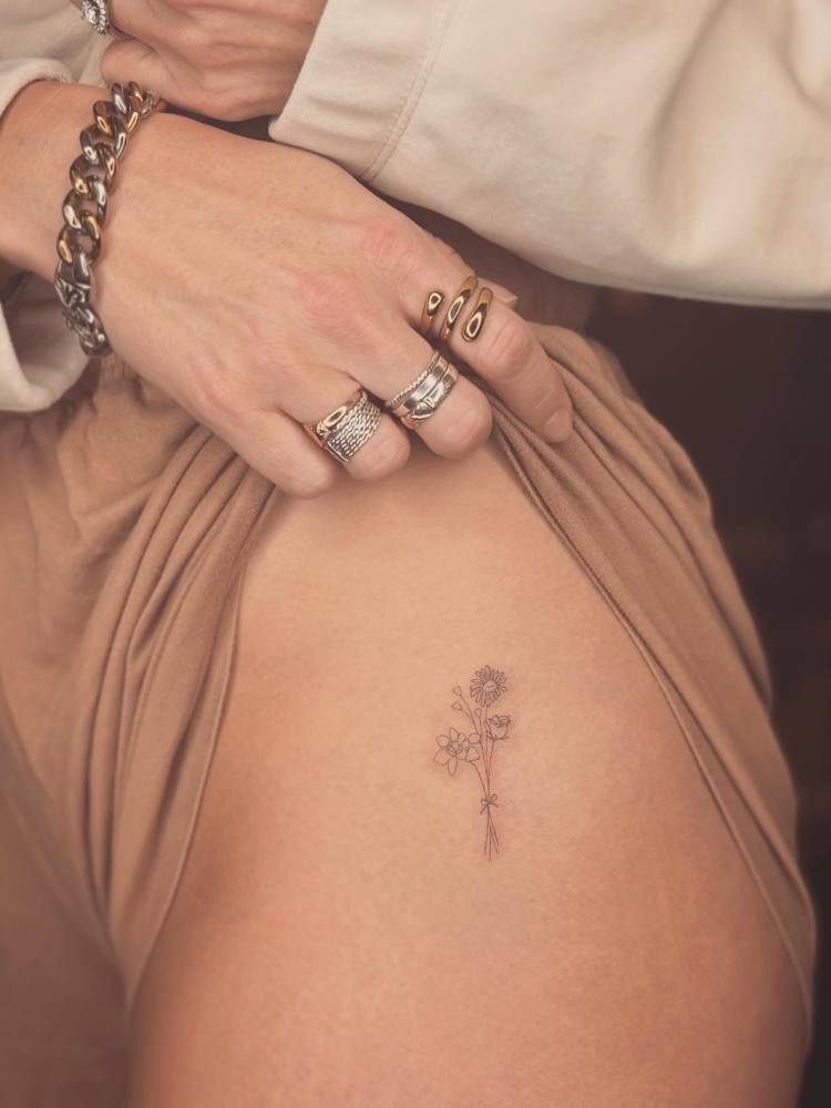 Fine line style flower bouquet tattoo located on the hip.