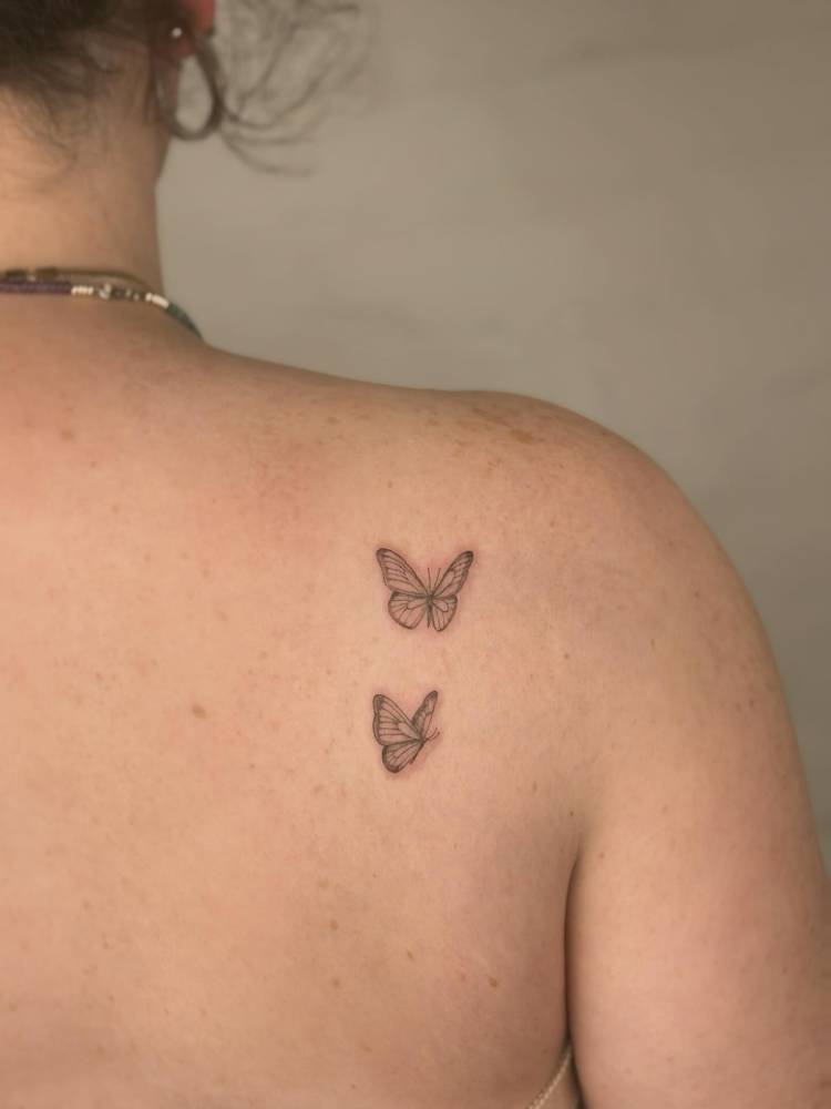 Butterfly couple tattoo in fine line style placed on the shoulder blade.