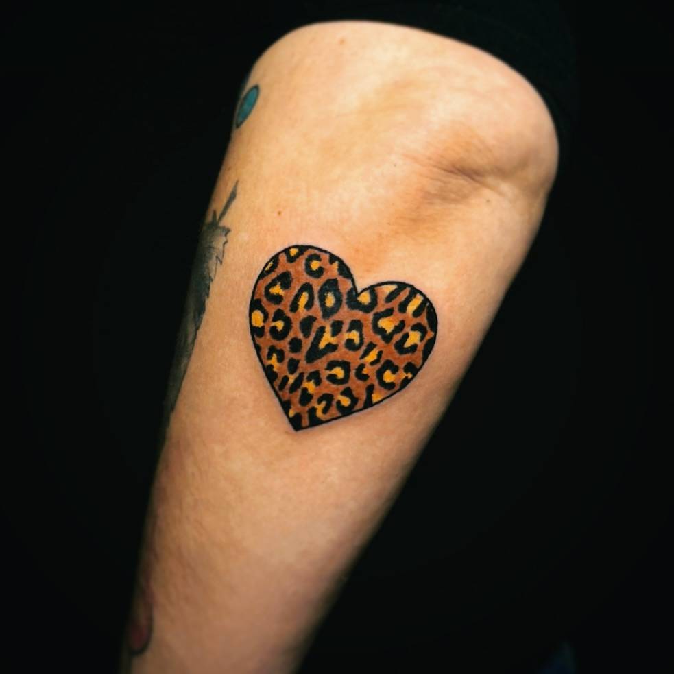 Leopard print heart tattoo hand poked on the forearm.