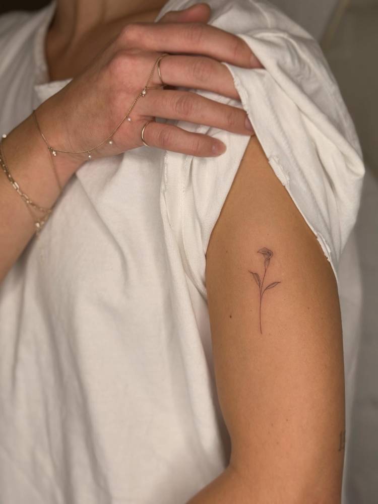 Calla lily flower tattoo placed on the upper arm.