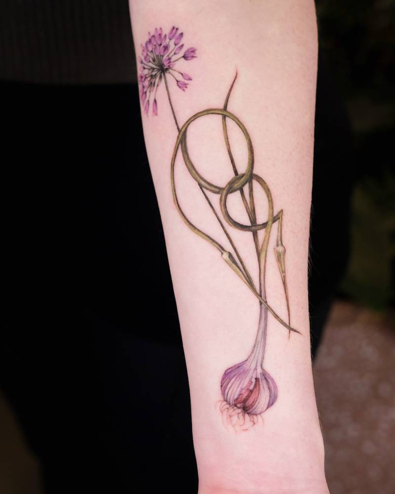 Watercolor style garlic tattoo located on the inner forearm.