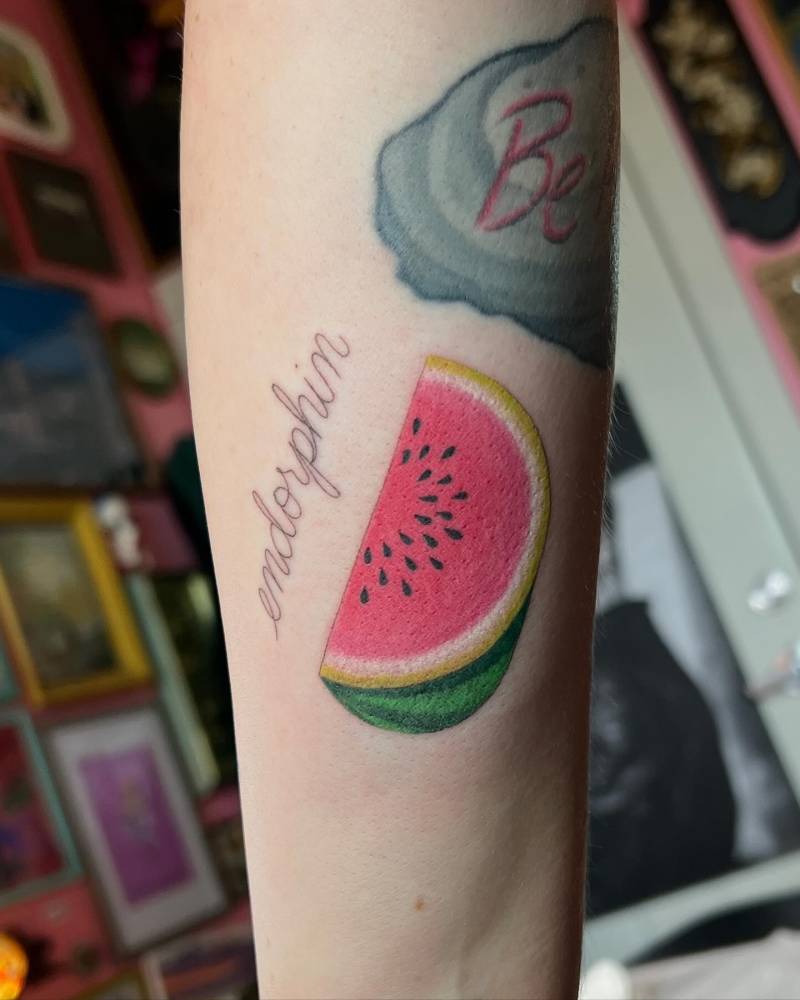 Illustrative style watermelon and word "endorphin" tattoo located on the inner forearm.