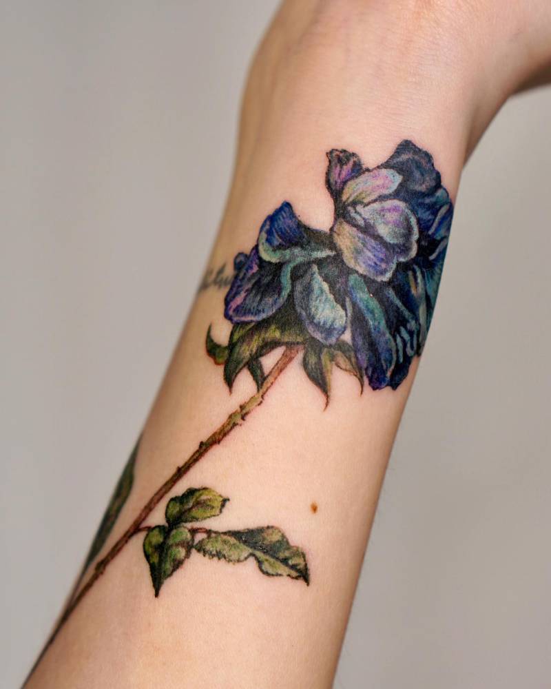 Watercolor style iris flower tattoo placed on the wrist.