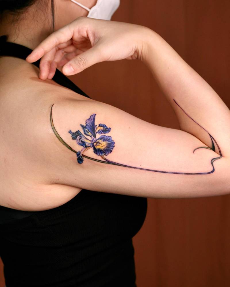 Iris flower tattoo located on the upper arm, done in watercolor style.