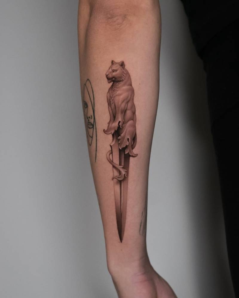 Panther dagger tattoo in micro-realistic style located on the forearm.