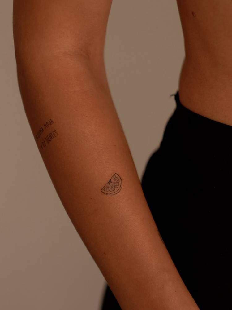 Lime slice tattoo in fine line style done on the forearm.