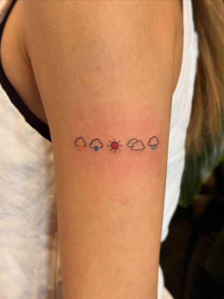 Weather symbols tattoo in minimalistic style done on the upper arm.