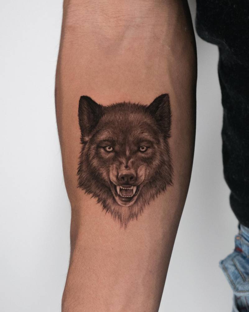 Wolf portrait tattoo in micro-realism located on the inner forearm.