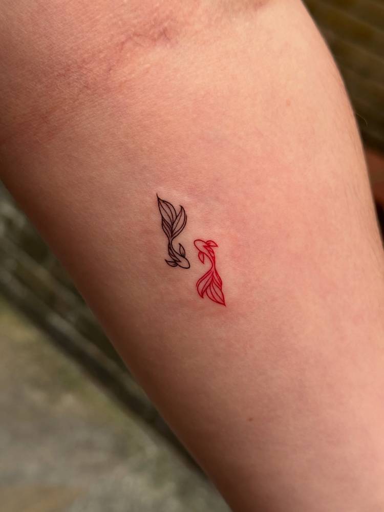 Two opposite fish tattoo in fine line style located on the inner forearm.