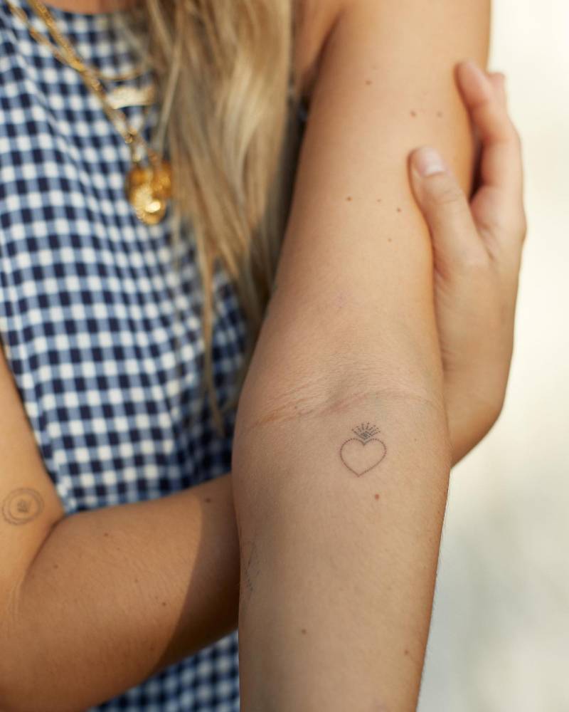 Minimalistic style flaming heart tattoo hand poked on the inner forearm.