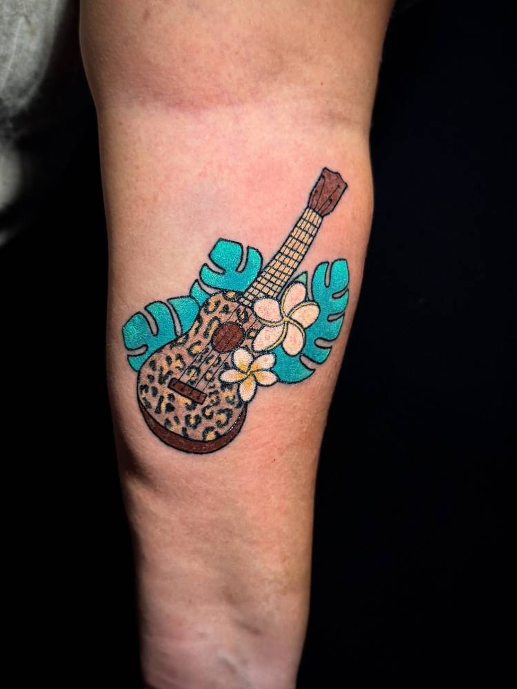 Hand poked leopard ukulele tattoo located on the inner forearm.