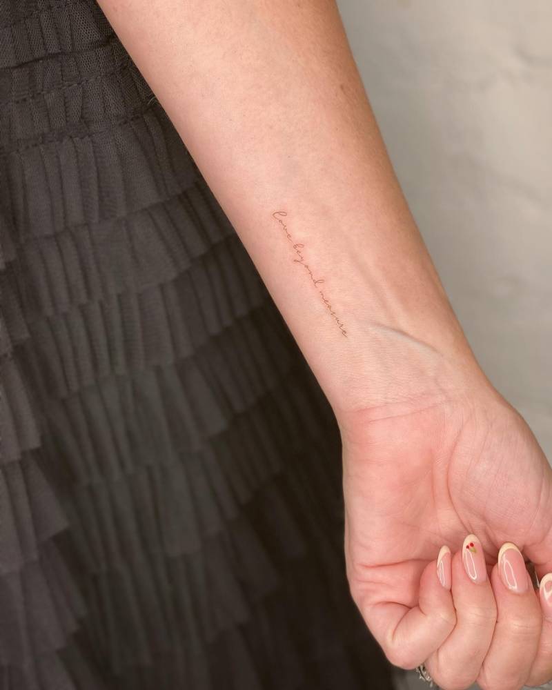 "Love beyond measure" lettering tattoo placed on the wrist.