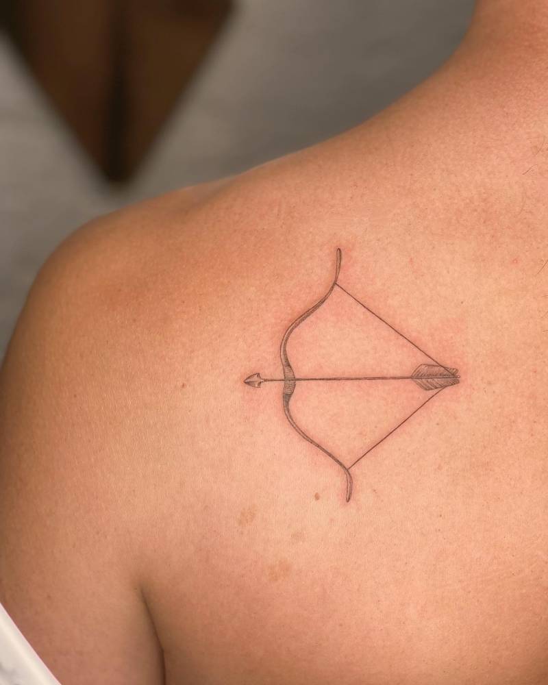 Bow and arrow tattoo in illustrative style placed on the shoulder blade.
