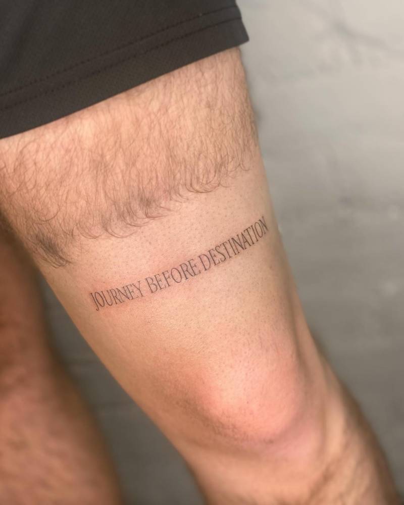 "Journey before destination" lettering tattoo placed on the thigh.