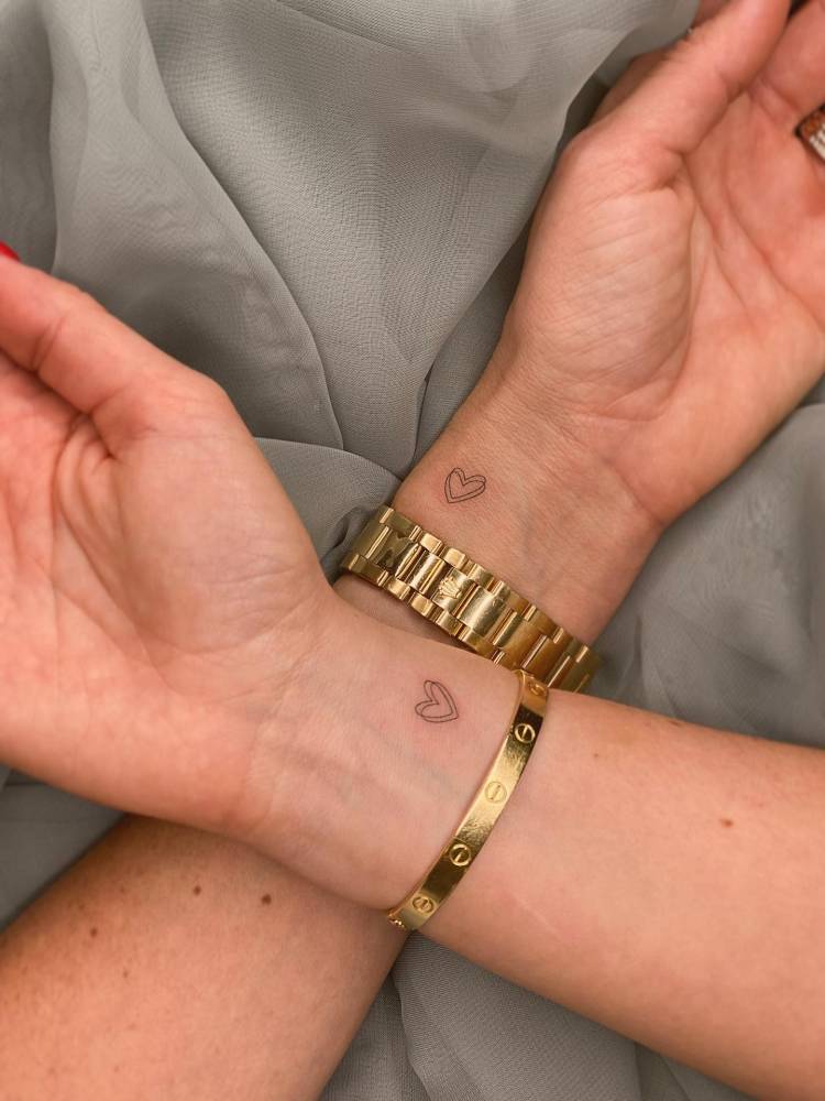 Matching minimalistic heart tattoo for couple.