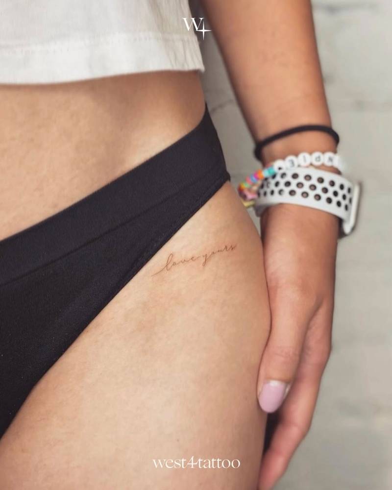 "Love yours" lettering tattoo handwritten on the pelvis.