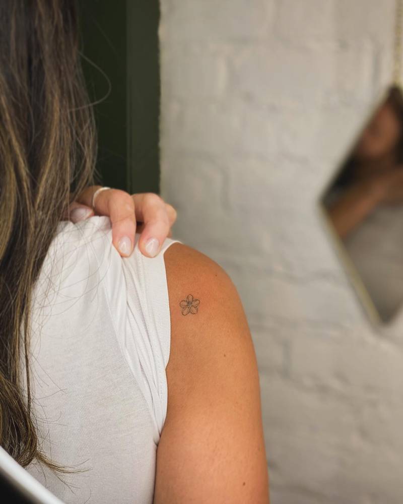 Fine line style plumeria tattoo located on the shoulder.