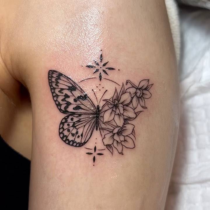 Illustrative style half butterfly half flower tattoo done on the upper arm.