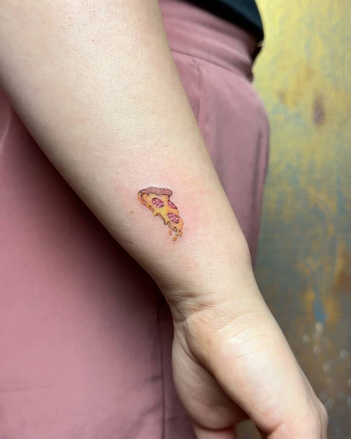 Tiny pepperoni pizza tattoo placed on the wrist, illustrative style.
