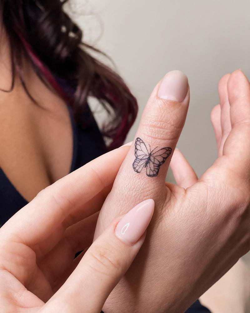 Tiny butterfly tattoo located on the thumb.