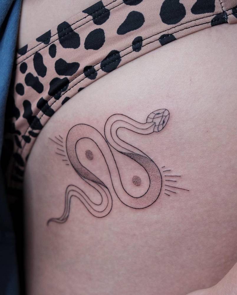 Illustrative style snake tattoo located on the pelvis.