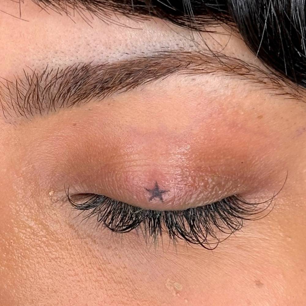 Hand poked minimalistic stars tattooed on the eyelids.