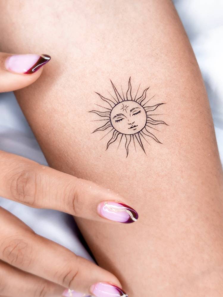 Inti tattoo in illustrative style located on the inner forearm.