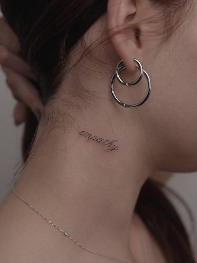 Script font word "empathy" tattooed on the neck.