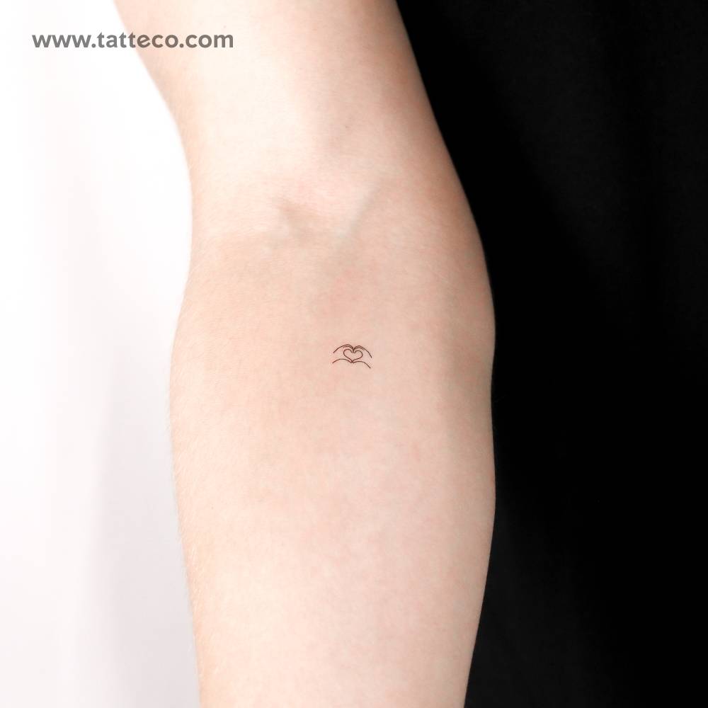 Tiny heart making hands temporary tattoo located on the inner forearm.