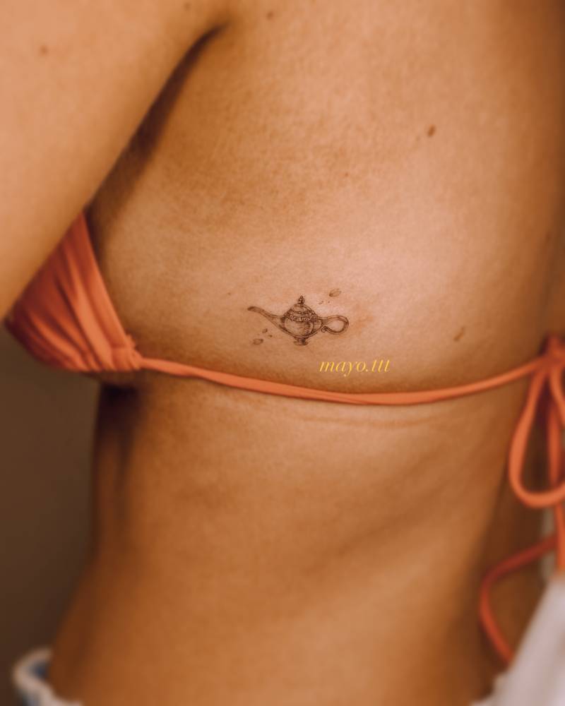 Genie lamp tattoo located on the side boob, illustrative style.