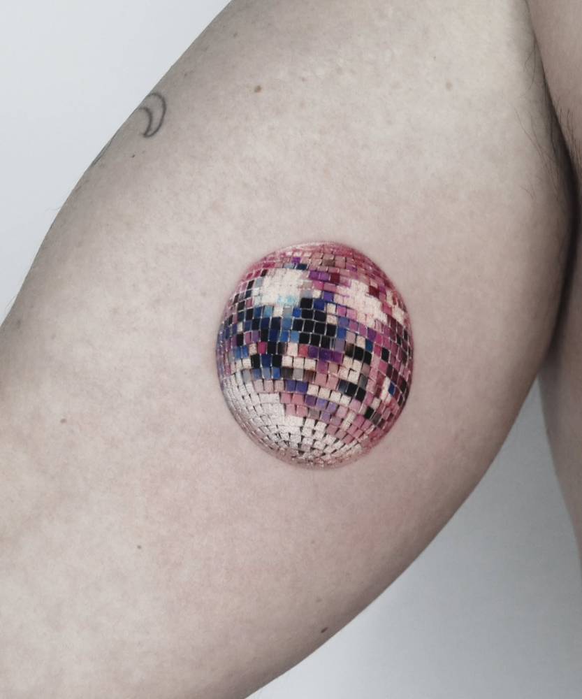 Micro-realistic style disco ball tattoo located on the inner arm.