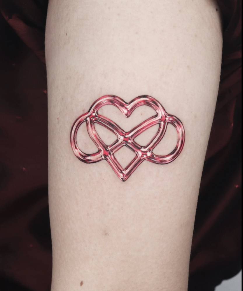 Metallic effect infinity heart tattoo done on the upper arm.