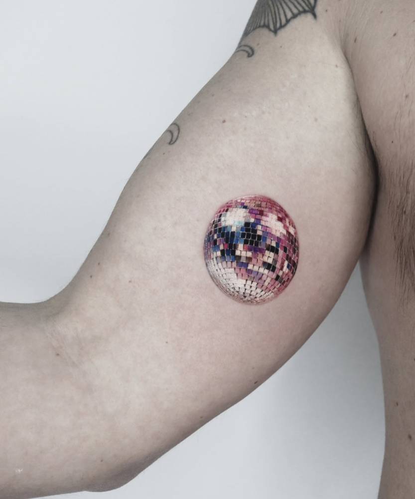 Micro-realistic style disco ball tattoo located on the inner arm.
