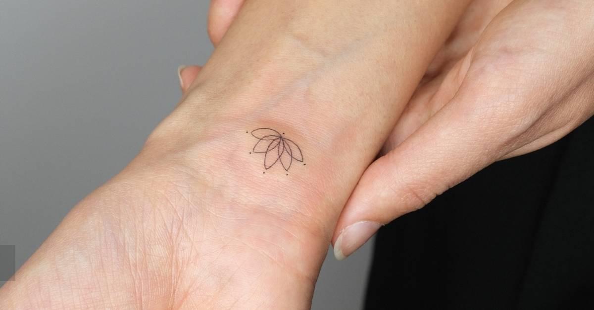 Tiny lotus flower tattoo in fine line style done on the