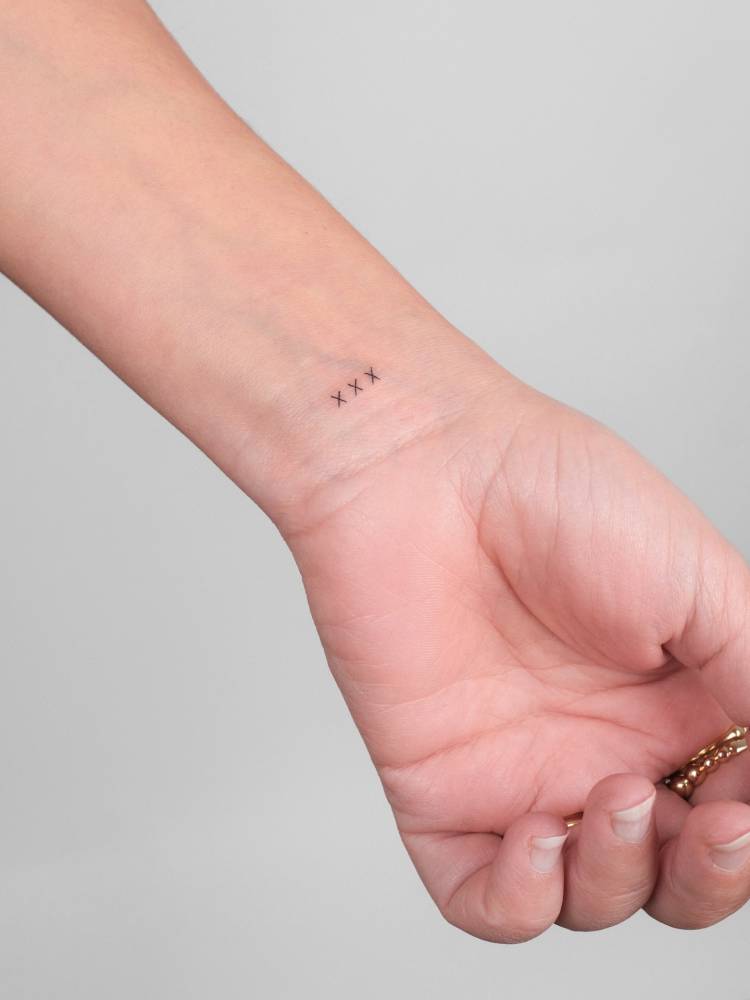 "XXX" lettering tattoo located on the wrist.